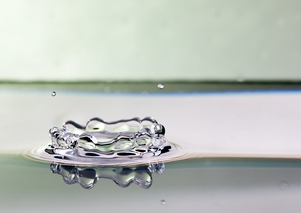 A splash of water forms a crown shape on a reflective surface.